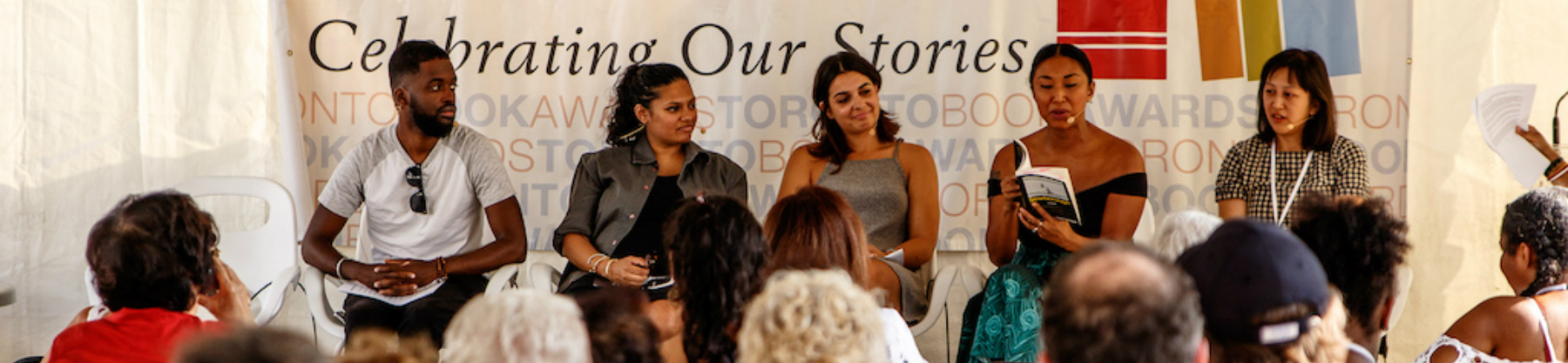 A panel of five authors sit on stage at the Word on the Street Book and Magazine Festival while answering questions from the audience.