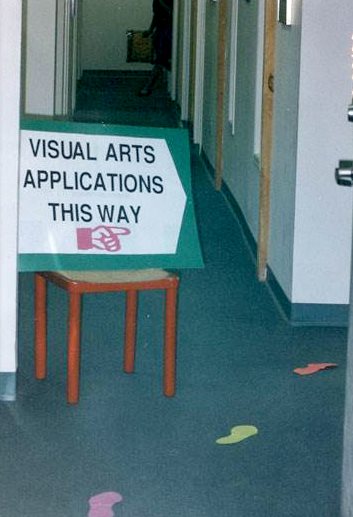 A sign that reads "Visual Artists This Way" rests on a chair